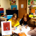 Dzieci rysują podczas zajęć w bibliotece, skupione na ilustracjach z książki "Gór Zmierzowiec".