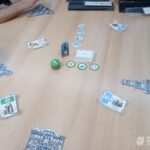 Stół pokryty elementami gry planszowej, kartami i żetonami w trakcie rozgrywki.