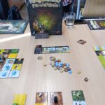 Na stole znajdują się elementy gry planszowej "Terraforming Mars", w tym karty, żetony i instrukcja.