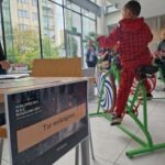 Chłopiec pedałuje na rowerze stacjonarnym podłączonym do urządzenia generującego energię.