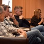 Uczestnicy Dyskusyjnego Klubu Książki siedzą w sali, słuchając dyskusji o powieści Marii Halber.