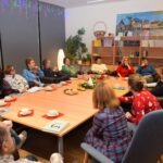 Uczestnicy Dyskusyjnego Klubu Książki siedzą przy długim stole podczas spotkania poświęconego powieści „Strużki”.