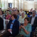 Publiczność siedzi w sali gimnastycznej i słucha koncertu zespołu Piosenki Odkopanej.
