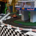Na torze wyścigowym znajdują się dwa samochodziki, a tory otacza dekoracja z flagą w szachownicę i logotypami Red Bull oraz X-Games.