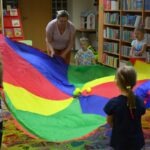 Dzieci bawią się na chustach Klanza podczas zajęć w bibliotece.