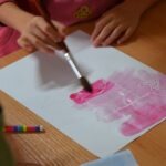 Dziecko maluje pędzlem różową farbę na papierze podczas eksperymentu z zabezpieczaniem dokumentów.