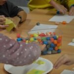 Dzieci układają kolorowe kuleczki, prawdopodobnie podczas budowy miniaturowych piramid.