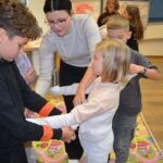 Dzieci w trakcie zajęć budują miniaturową piramidę, a jedna z nich jest przebrana za mumie.