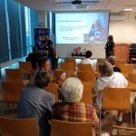 Seniorzy uczestniczą w prezentacji dotyczącej bezpieczeństwa cyfrowego podczas spotkania organizowanego przez ISSA Polska.