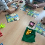 Ludzie bawią się w gry planszowe na podłodze podczas wydarzenia w bibliotece.
