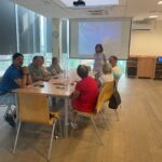 Grupa seniorów uczestniczy w warsztatach fotograficznych w bibliotece.