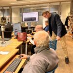 Mężczyzna instruuje starszego uczestnika podczas zajęć w Klubie Rozwoju Cyfrowego.