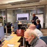 Uczestnicy zajęć obserwują prezentację na ekranie podczas spotkania Klubu Rozwoju Cyfrowego.