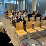 Grupa osób siedzi w sali konferencyjnej, słuchając prelekcji o Portugalii.