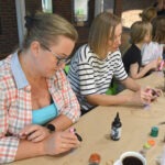 Kobiety skupiają się nad tworzeniem ozdób z żywicy epoksydowej podczas warsztatów rękodzielniczych.