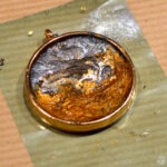 Ozdobny medalion z żywicy epoksydowej leży na zielonym podłożu.