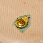 Żółta zawieszka z żywicy epoksydowej leży na zielonym podkładzie.