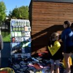 Dzieci oglądają wystawę plakatów informujących o lokalnej faunie i florze podczas pikniku edukacyjnego.