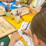 Dzieci malują kolorowanki podczas zajęć plastycznych w bibliotece.