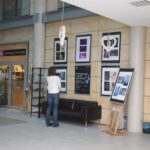 Kobieta ogląda wystawę fotografii w galerii miejskiej.