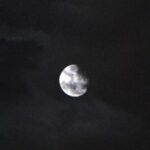 Widok księżyca w fazie sierpnicy na tle nocnego nieba i chmur.