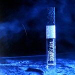 Mascara Maybelline Snapscara stoi na mokrym, niebiesko podświetlonym podłożu.