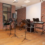 W sali biblioteki ustawiono mikrofony, statywy z nutami oraz instrumenty muzyczne gotowe do występu.