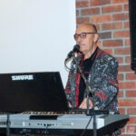 Muzyk gra na keyboardzie, śpiewając do mikrofonu podczas koncertu.