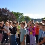 Grupa dzieci uczestniczy w pikniku edukacyjnym podczas Europejskiego Dnia Bez Samochodu.