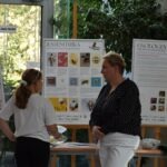 Kobiety rozmawiają przed plakatami informacyjnymi o lokalnej faunie i florze.