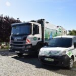 Na parkingu zaparkowana jest śmieciarka oraz samochód dostawczy, oba oznakowane logo firmy MIKI Recykling.