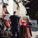 Mężczyzna pomaga dziewczynce wsiąść do mobilnej rowerowej czytelni podczas pikniku edukacyjnego.