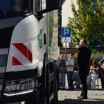 Ciężarówka zaparkowana jest w pobliżu znaku informującego o możliwości parkowania.