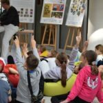 Uczniowie podnoszą ręce podczas warsztatów edukacyjnych poświęconych ochronie środowiska.