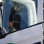 Mężczyzna siedzi za kierownicą białego samochodu dostawczego.
