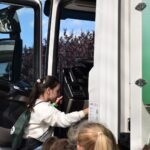 Dziewczynka podchodzi do drzwi autobusu podczas wydarzenia promującego alternatywne formy transportu.