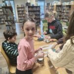 Dzieci tworzą lampiony podczas warsztatów w bibliotece.