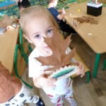 Dziecko prezentuje wykonaną z liści i drewna figurkę jeża podczas zajęć plastycznych w przedszkolu.