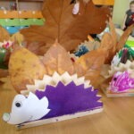 Wykonane przez dzieci jeżyki z drewna i liści prezentują się wśród jesiennych dekoracji.