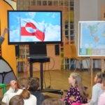 Na ekranie wyświetlana jest flaga Grenlandii w trakcie prezentacji dla dzieci.