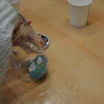 Dziecko wylewa zawartość słoika na drewniany blat.