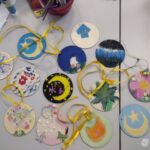 Dzieci stworzyły kolorowe ozdoby z motywami księżyca, gwiazd i roślin podczas warsztatów plastycznych w bibliotece.