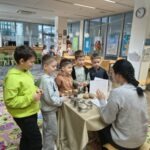 Grupa dzieci obserwuje wystawę przypraw podczas zajęć edukacyjnych.