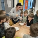 Nauczycielka prowadzi eksperyment z cieczą nienewtonowską podczas zajęć dla dzieci.