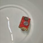 Czerwony model statku z elementami drewnianymi leży na białej powierzchni.