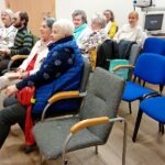 Uczestnicy spotkania Dyskusyjnego Klubu Filmowego siedzą na krzesłach w sali konferencyjnej.