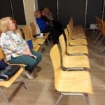 Na zdjęciu widoczni są uczestnicy spotkania, siedzący w rzędach krzeseł w sali konferencyjnej.