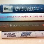 Na stosie leżą książki z tytułami: "Poświatowska", "Biografia Poświatowskiej", "Herbert" i "Wiersze".