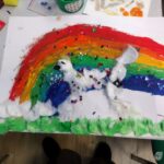 Dziecięca praca przedstawia tęczę nad bałwankiem wykonanym z białej masy papierowej i kolorowych elementów.