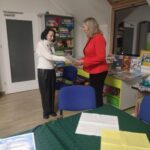 Dwie kobiety podają sobie ręce podczas spotkania w bibliotece.